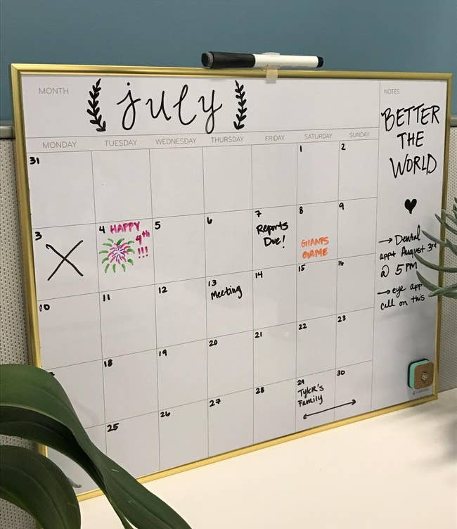 Whiteboard calendar with a gold-tone border handwritten events