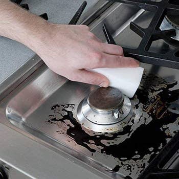 a thick white cleaning pad being used to clean a burner on a stove