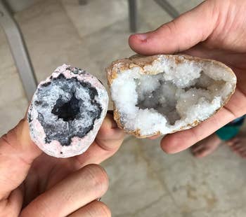 Two hands holding 2 chopped geodes, revealing sparkling crystal interiors