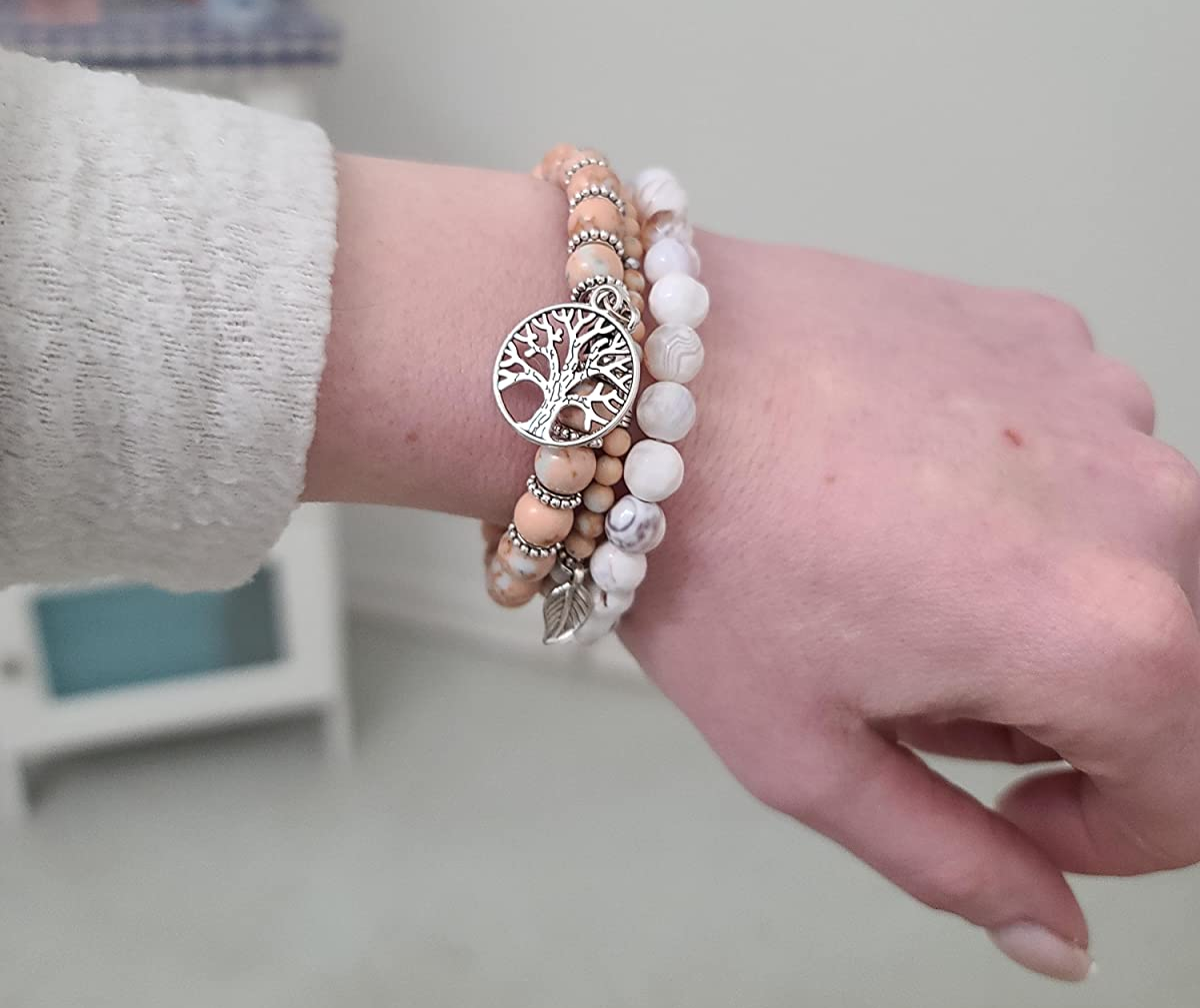 Reviewer wearing light pink and white marble patterned beads with a tree of life charm and leaf charm