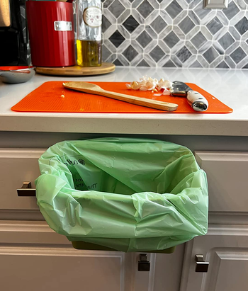 a reviewer photo of the bin lined with a compostable bag attached to a drawer 