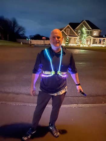 reviewer wears blue and purple illuminated reflective vest while walking outside at night