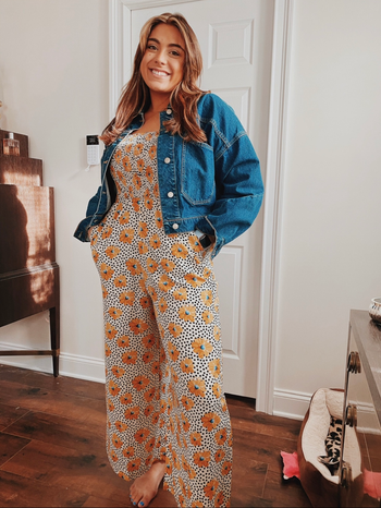 a reviewer posing in the orange floral jumpsuit
