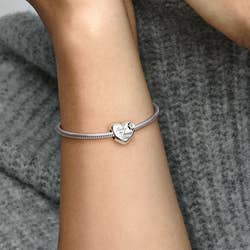 model wearing a silver bracelet with heart charm on it