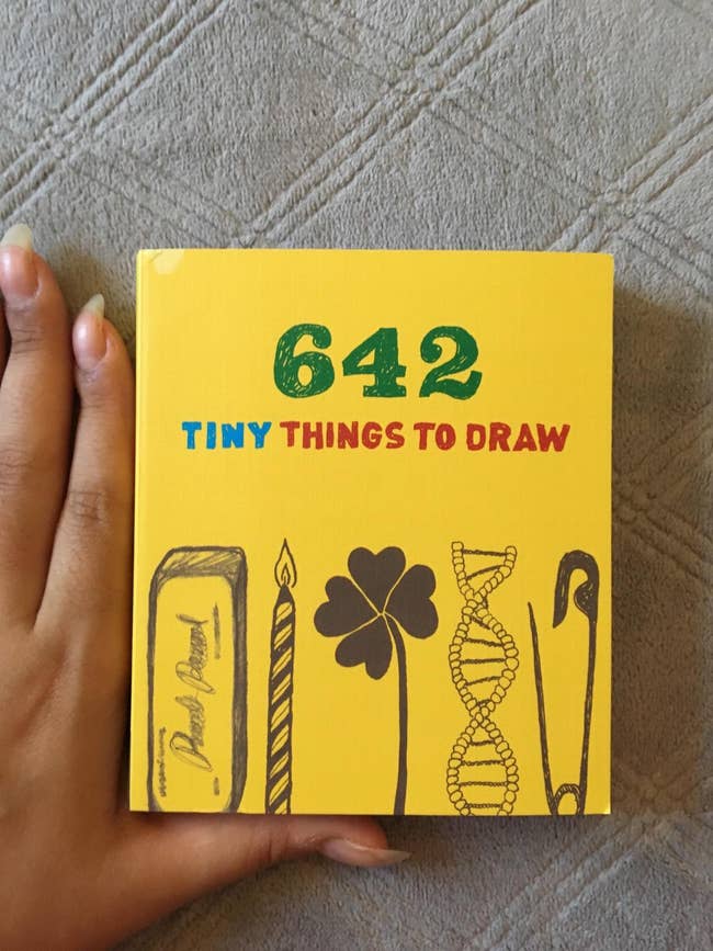 A customer review photo of the 642 Tiny Things To Draw book with their hand next to it for scale