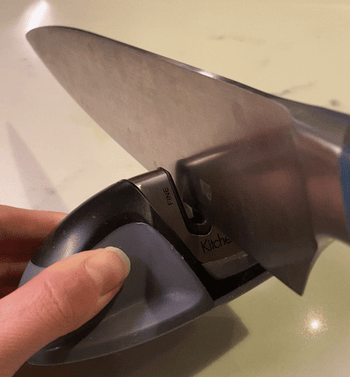 gif of BuzzFeeder running a knife through the knife sharpener
