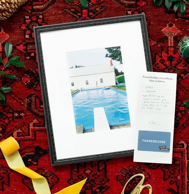 a framed photo next to a gift card with a personalized note 