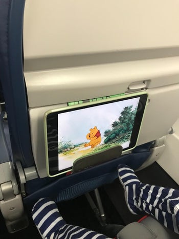 another reviewer photo of a toddler watching winnie the pooh on a tablet that's sitting in the holder