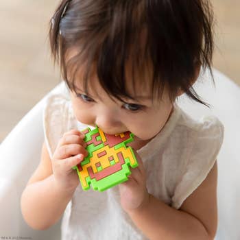 Toddler with a teether. Toy resembles a classic video game element