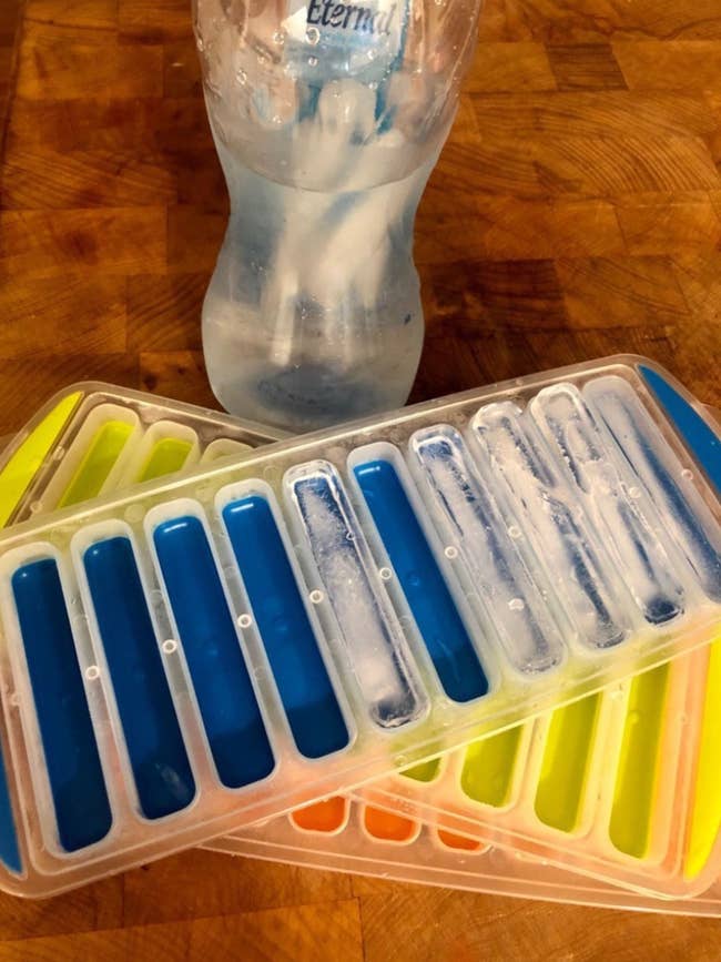 Reviewer image of three ice trays next to a water bottle with ice sticks in it 