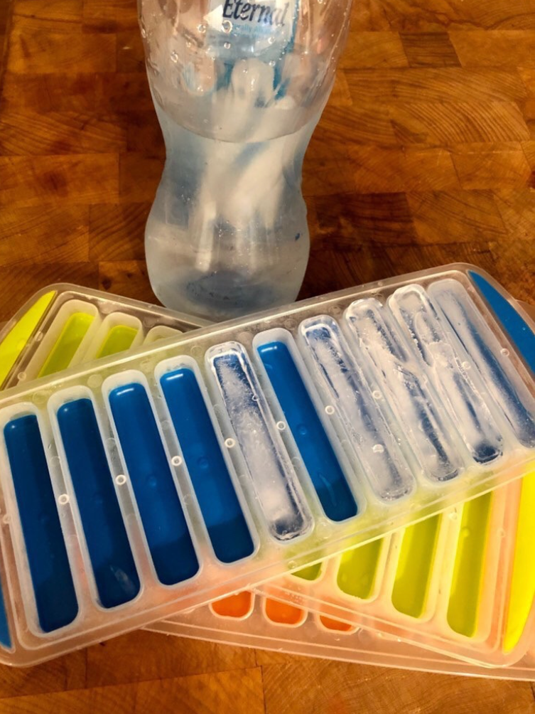 Reviewer image of three ice trays next to a water bottle with ice sticks in it 