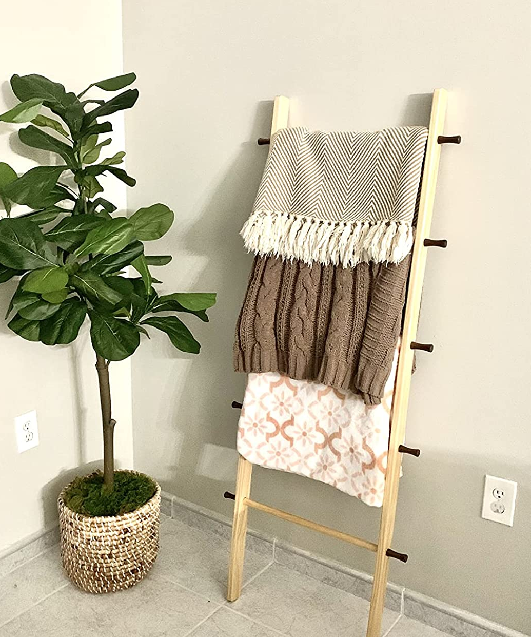 a reviewer photo of a wooden ladder with blankets hanging on each rung leaning against a wall 