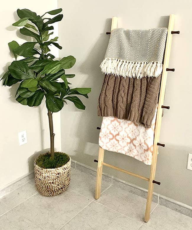 a reviewer photo of a wooden ladder with blankets hanging on each rung leaning against a wall 