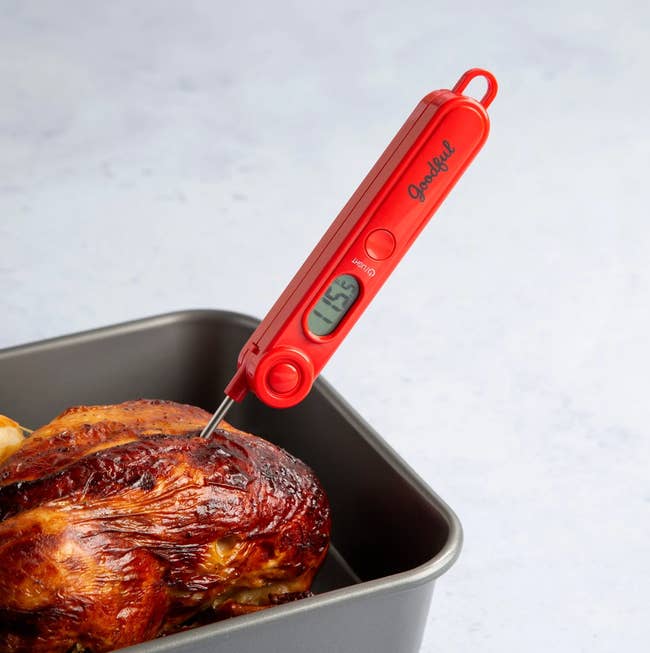 The food thermometer sticking out of chicken in a pan