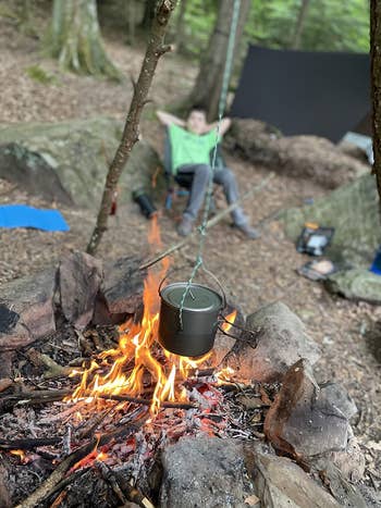 reviewer photo of hanging pot over campfire, child in the background