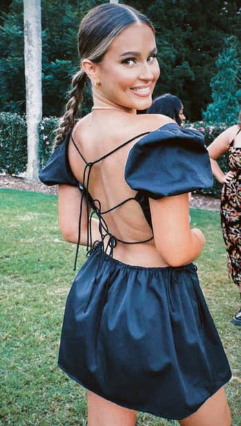 A model wearing the dress showcasing the open back laced up with straps