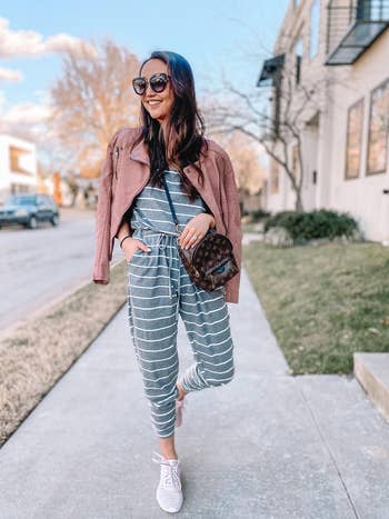 a reviewer wearing the jumpsuit in grey with white stripes