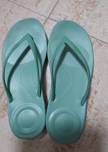 reviewer photo of the teal flip-flops, showing their cushioned soles