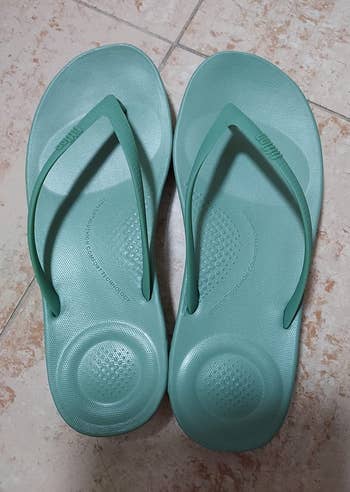 reviewer photo of the teal flip-flops, showing their cushioned soles