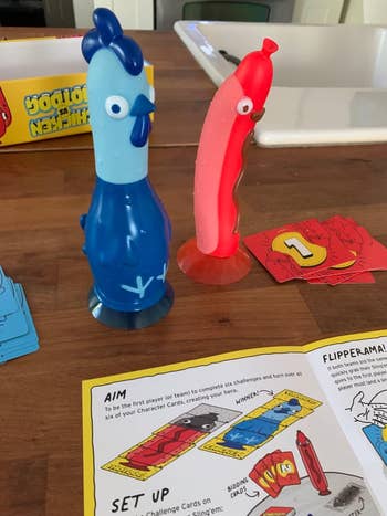 Two character-shaped game pieces on a table with instructions and cards from a game visible