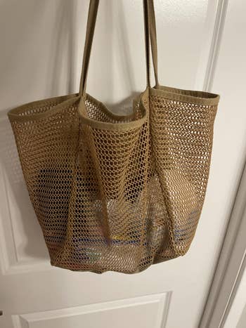 Mesh tote bag hanging on a door, showcasing its design and spaciousness