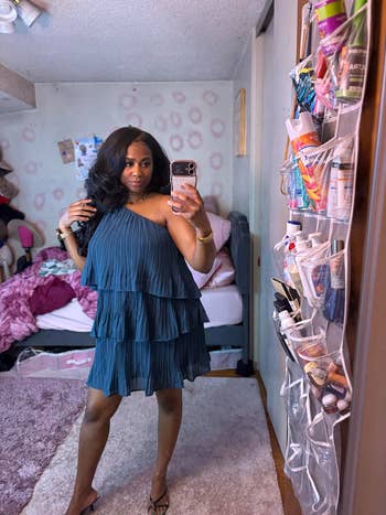 Person successful  a sleeveless, tiered formal  takes a reflector  selfie successful  a bedroom. Background shows toiletries and decor items