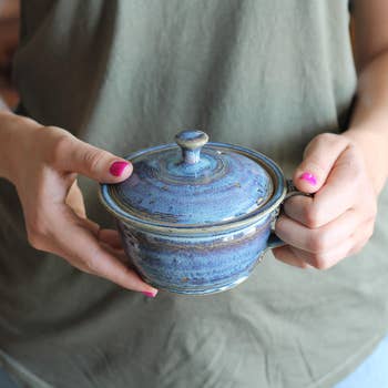 Model holding rustic blue small pot-shaped cooker 