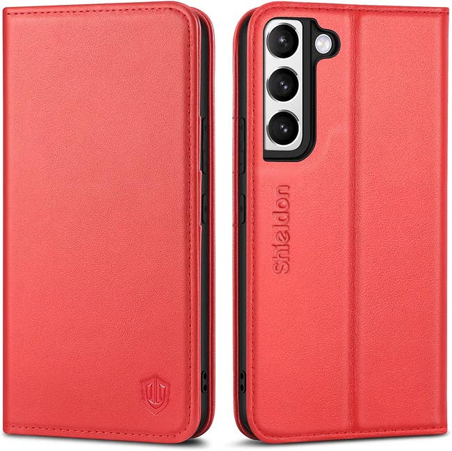 Front and back view of coral leather phone case with stitching around edges and shield engraved on bottom corner on a white background