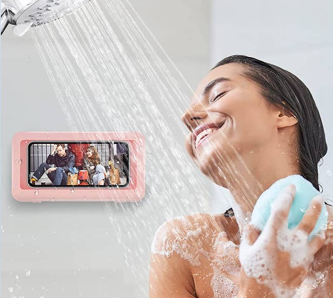 model showering while watching something on their phone, which is in the pink phone mount