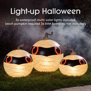 Three inflatable pumpkins with light-up mummy designs connected  grass. Includes multi-color lights but requires 3  AAA batteries per pumpkin