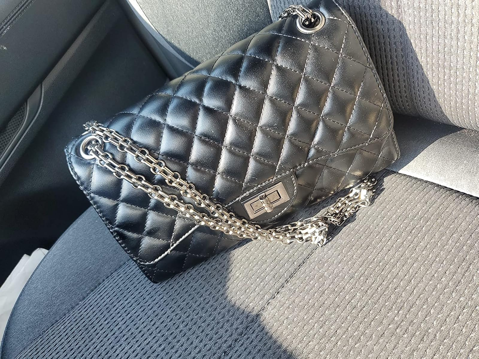 Quilted leather handbag with concatenation  strap connected  a car   seat