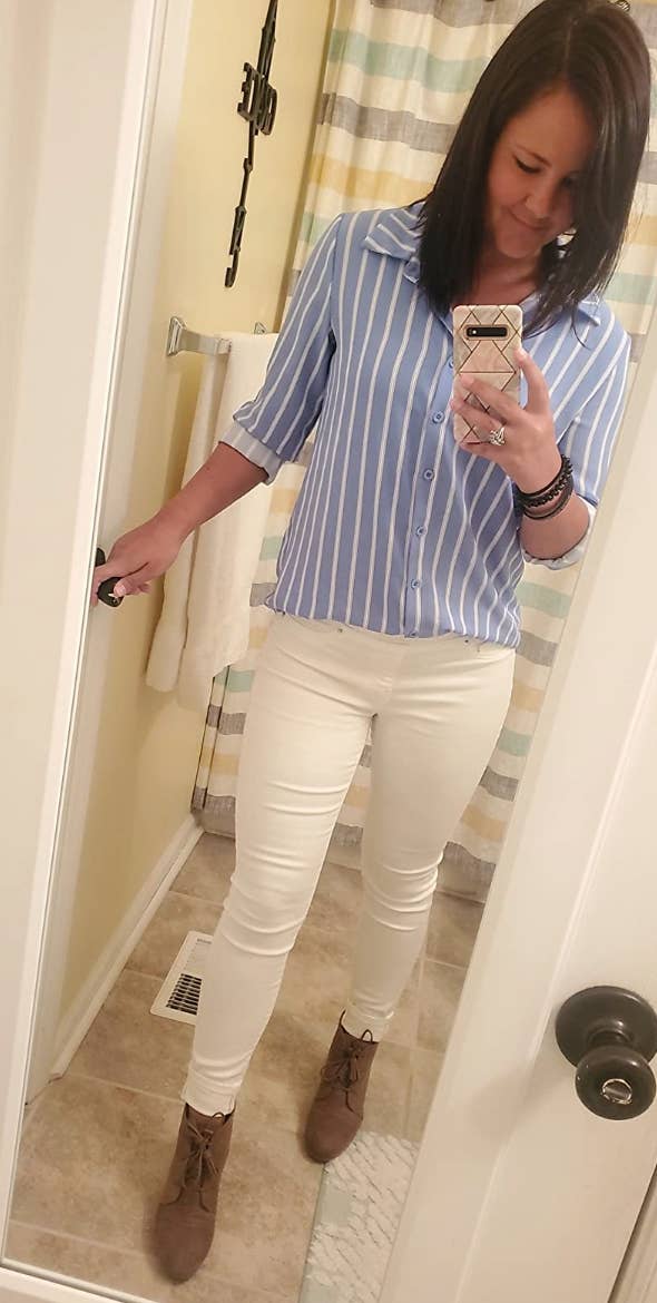 Reviewer is wearing a white and light blue vertical striped button down top with white pants and beige wedges