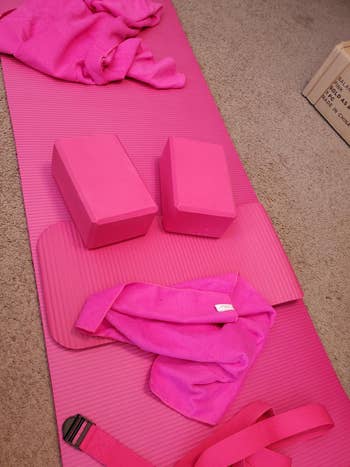 Yoga mat with 2  blocks, towel, and strap, each  connected  a carpeted floor; items person  a cohesive look   for workout routines