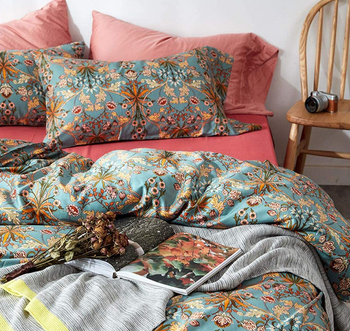 the bed with pink sheets and a blue printed duvet and matching pillows 