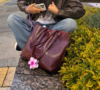 Person sitting connected  pavement with a ample  textured handbag