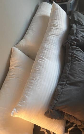 Reviewer image of the white pillow on their bed with other pillows