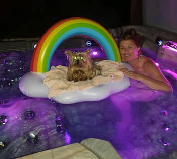 a idiosyncratic successful a blistery tub with a tiny canine connected a rainbow unreality float, surrounded by colorful lights