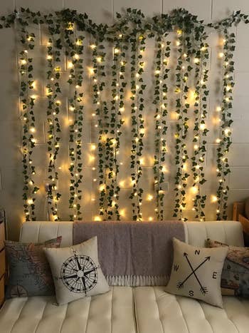 a sofa with the faux vines and twinkle lights hung behind it 