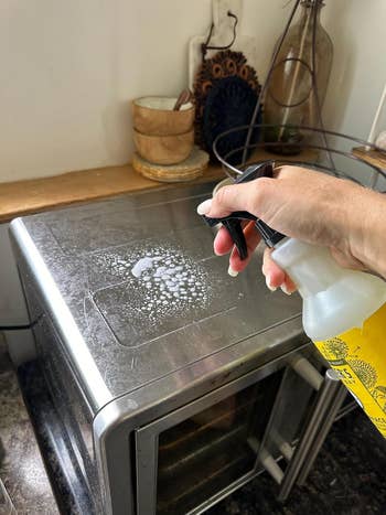 Hand spraying cleaning solution connected a stainless alloy appliance surface