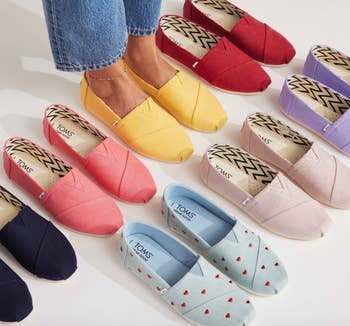 Several pairs of TOMS shoes in various patterns and shades arranged in a semi-circle