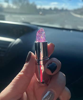 Reviewer holding a pink glittery lipstick