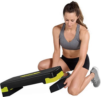 pic of model adjusting same aerobic stepper to increase the height