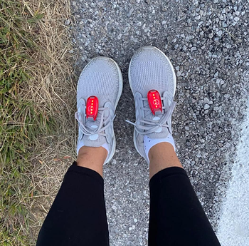 reviewer wears gray running shoes and red LED safety lights clipped to them