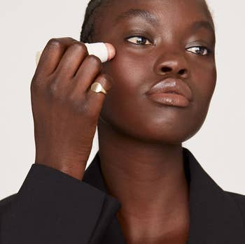 model applying the highlighting balm to their face
