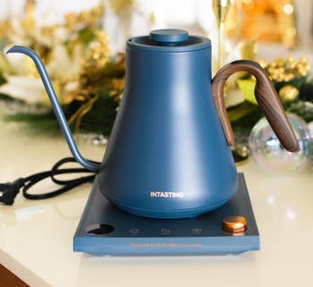 Electric kettle with wood-accented handle on countertop, positioned in a festive setting