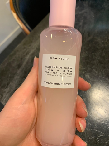 Reviewer holding pink bottle of product 