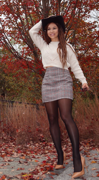 reviewer wearing the gray plaid skirt with tights and a cropped sweater