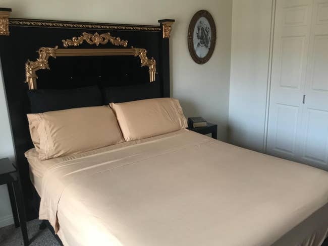 Elegant furniture with ornate headboard, golden details, and beige bedding successful a stylish chamber setting