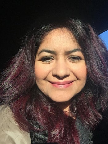 Reviewer with black and red shiny smooth hair and a tan jacket