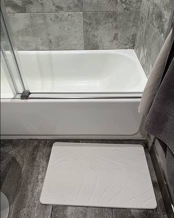 reviewer's white rectangle shaped bath stone in front of a tub 